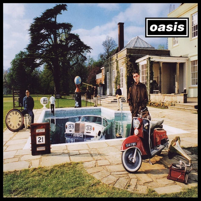 The cover artwork for 'Be Here Now' showing the band outside a grand country house with various items around inclusing a Rolls Royce in a full swimming pool and a red scooter and gramophone in the foreground