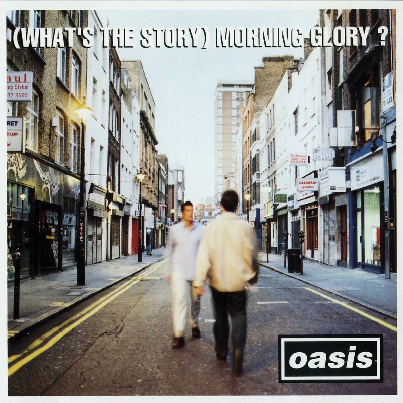 The cover art to (What's The Story) Morning Glory?, showing two figures walking in opposite directions in a city street, very close to each other